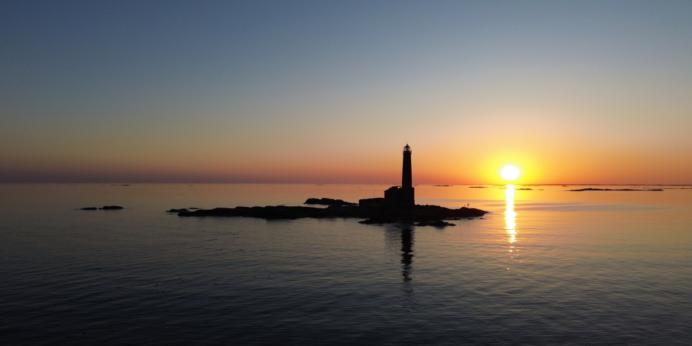 The island of Bengstkär, with a high lighthouse, in front of the sunset